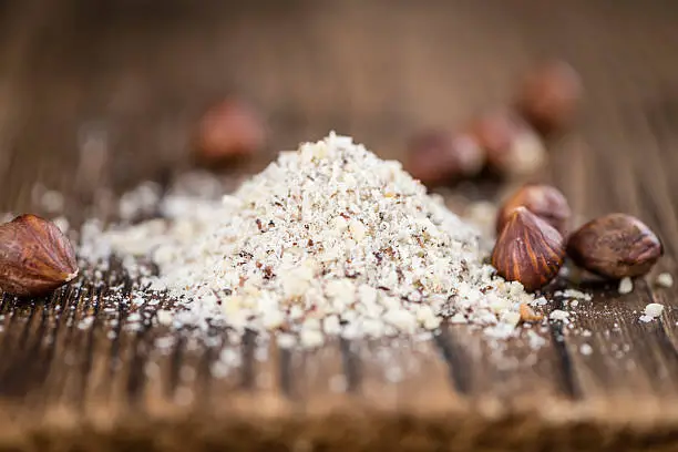 Hazelnuts (grounded) on vintage wooden background (selective focus; close-up shot)