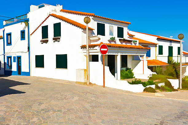 A charming, uphill street in Torres Novas, Portugal, lined with traditional white buildings and an ornate balcony under a clear blue sky.