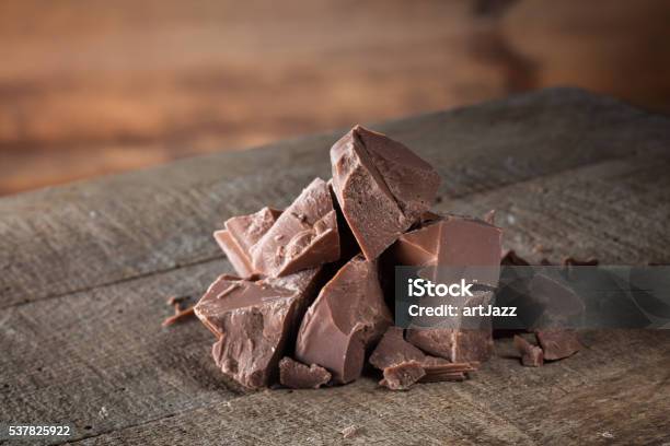 Pieces Of Milk Chocolate On Wood Stock Photo - Download Image Now - Baked Pastry Item, Black Color, Block Shape