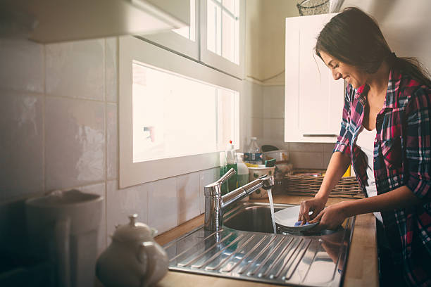 Washing Dishes Cute lovely woman standing and washing dishes bath sponge photos stock pictures, royalty-free photos & images