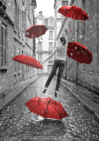 Girl with red umbrellas flying above-ground. Conceptual, surreal image. Black and white pictures with red elements.