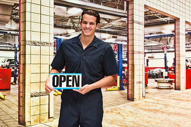 istock Happy mechanic holding open sign in auto repair shop 537835310