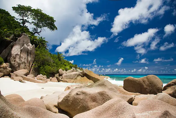 Typical granite rocks a turquoise ocean view with white clouds on blue skyTypical granite rocks a turquoise ocean view with white clouds on blue sky