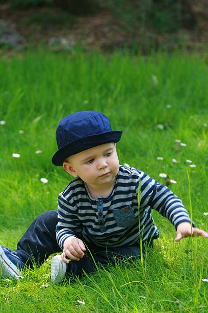 istock Blue Eyes Child with Blue Hat Touching a Flower 537844476