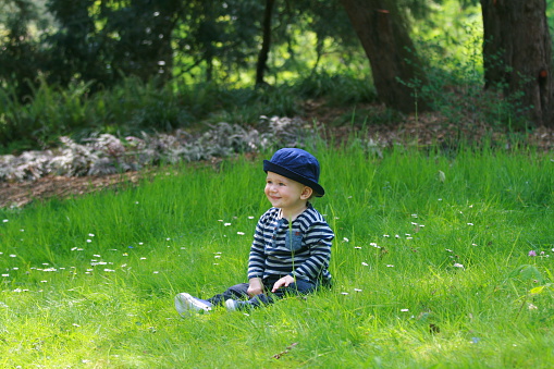Child in the grass with forrest background - Bagatelle Park, Paris, France