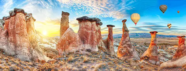 Rocks looking like mushrooms dramatically lit by a sunset in Cappadocia, Turkey. With balloons