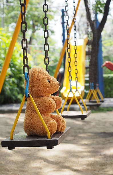 istock Teddy bear toy sitting alone on chain swing on kids playground 537850482