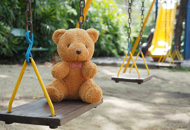 istock Teddy bear toy sitting alone on chain swing on kids playground 537850694
