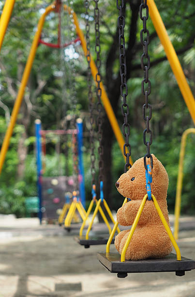 istock Teddy bear toy sitting alone on chain swing on kids playground 537850862