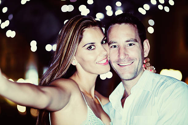 istock Great date! Smiling couple taking souvenir Selfie under twinkling lights 537854107