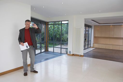 Full length of a male real estate agent photographing new property