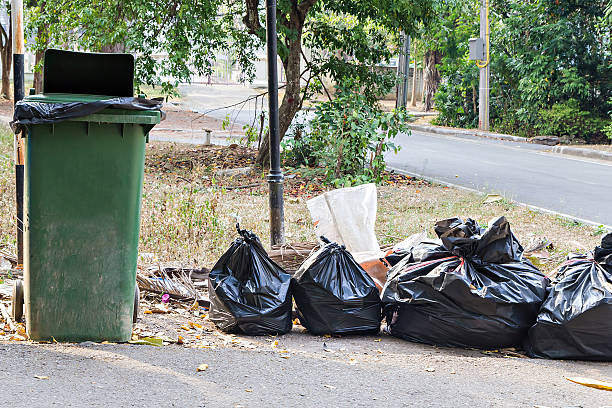 istock Old green bin and pile of full garbage bags 537865722