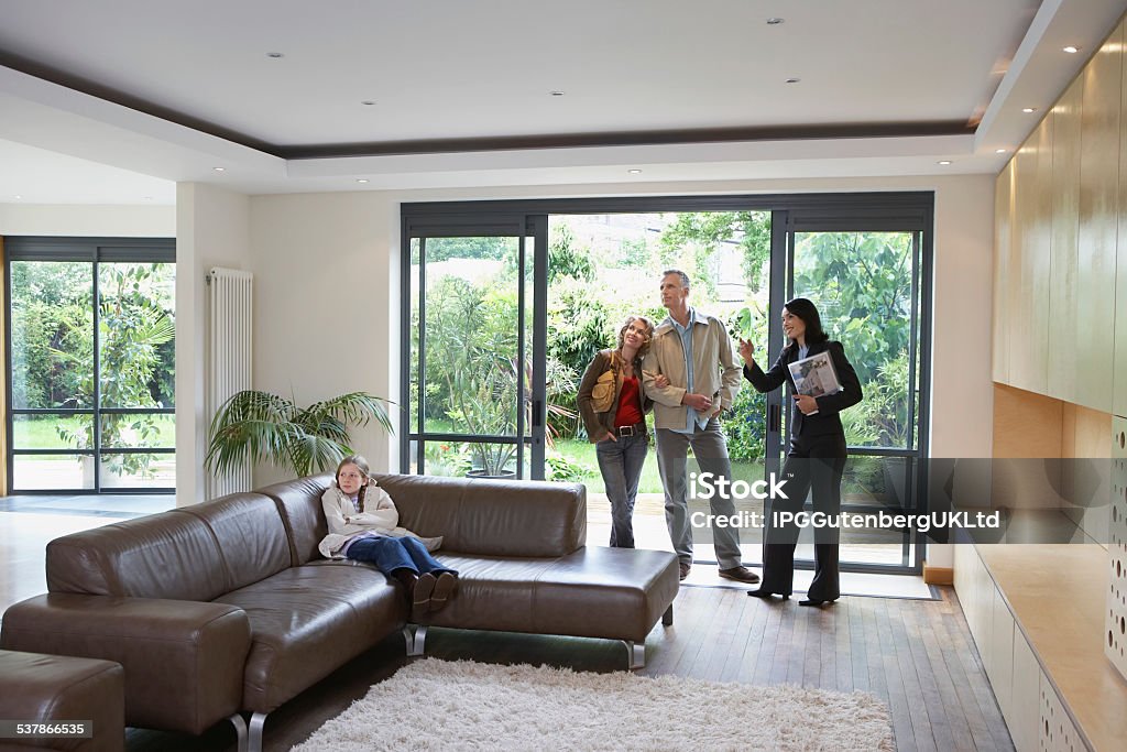 Family And Estate Agent Observing New Property Parents with daughter and female estate agent observing new property Real Estate Agent Stock Photo