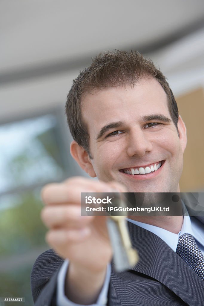 Real Estate Agent Holding Out House Key Portrait of a happy male real estate agent holding out house key 2015 Stock Photo