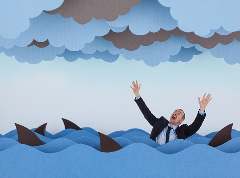 Businessman surrounded by sharks in stormy sea. Competitive business concept