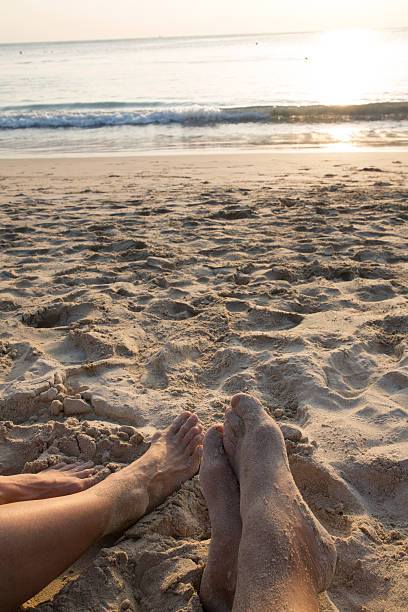 istock Couple's feet relax on white sand beach, sunrise 537871427