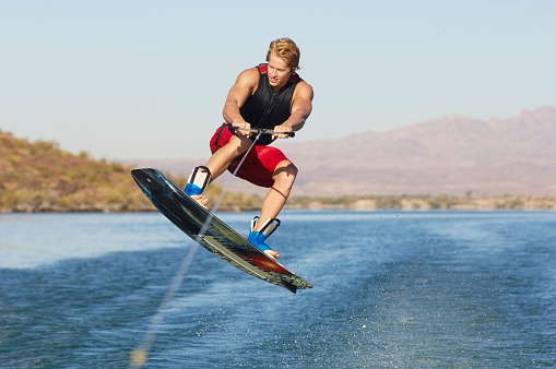A young wake boarder in midair while wakeboarding on lake
