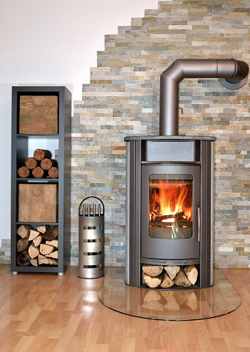 burning wood fired stove with fire-wood, fire-irons and briquettes