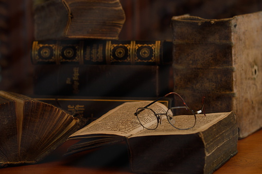 antique books with reading glasses in a dusty room