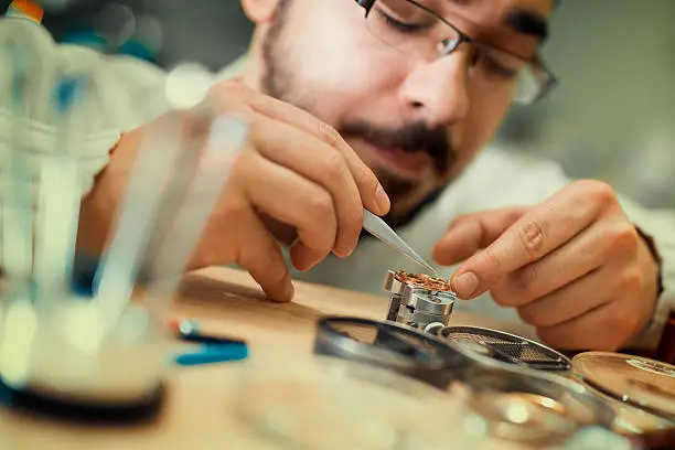 Close up portrait of a watchmaker at work.He is wearing specialist magnifying glass.
