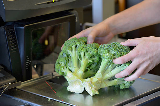 Weighing broccoli at a self check out at a supermarket Close up of a person weighing broccoli at a  self check out counter at a supermarket self checkout photos stock pictures, royalty-free photos & images