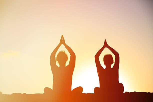 istock silhouette of couple doing yoga at sunset 537891380