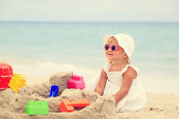 istock cute little girl play with sand on beach 537891534