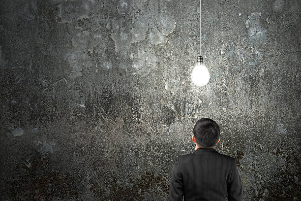 istock Businessman looking at brightly light bulb illuminated dark conc 537891739