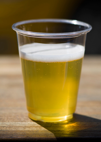 A refreshing pint of cold beer on a wood surface with white background.