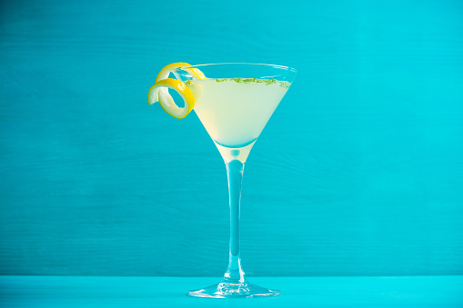 Yellow martini cocktail with lemon and mint on the rustic wooden background
