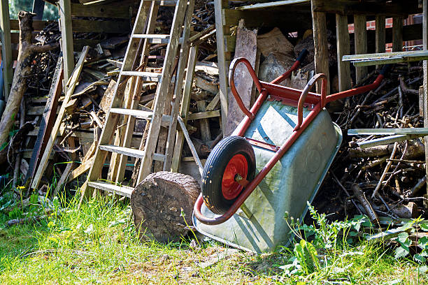 wheelbarrow leaning overhead on a shed in a country garden - skräpig trädgård bildbanksfoton och bilder