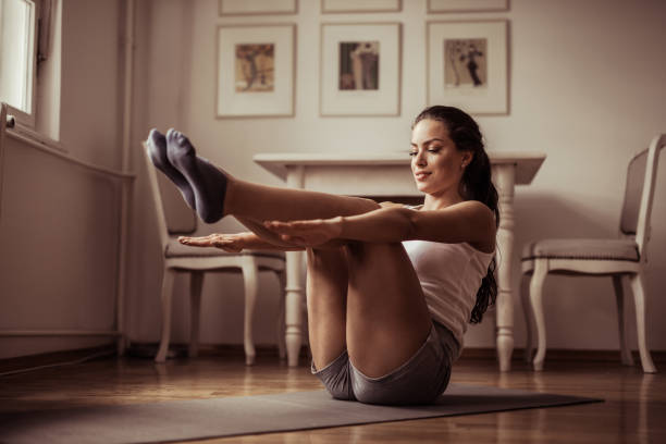 atlético joven sonriente mujer haciendo abdominales en su hogar. - sit ups fotografías e imágenes de stock