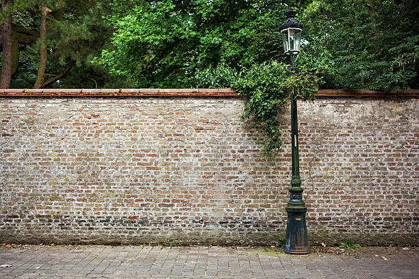 Street light in front of old gray stone brick wall