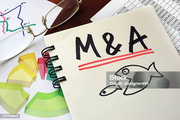 Ma Merger And Acquisitions Written On A Notepad Stock Photo - Download Image Now - Mergers and Acquisitions, Strategy, Adult