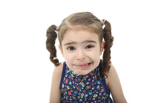 Surprised young girl looking at camera against gray studio wall background