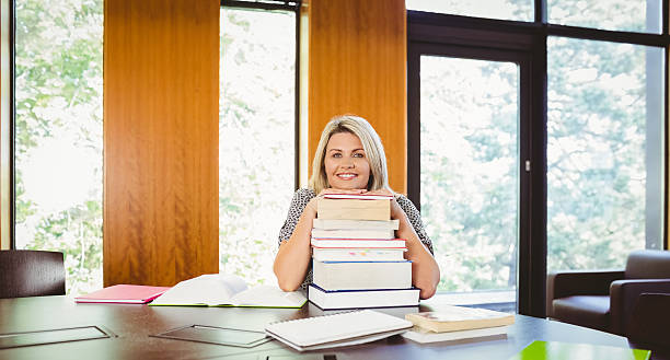 istock Smiling blonde mature student with stack of books 537954565