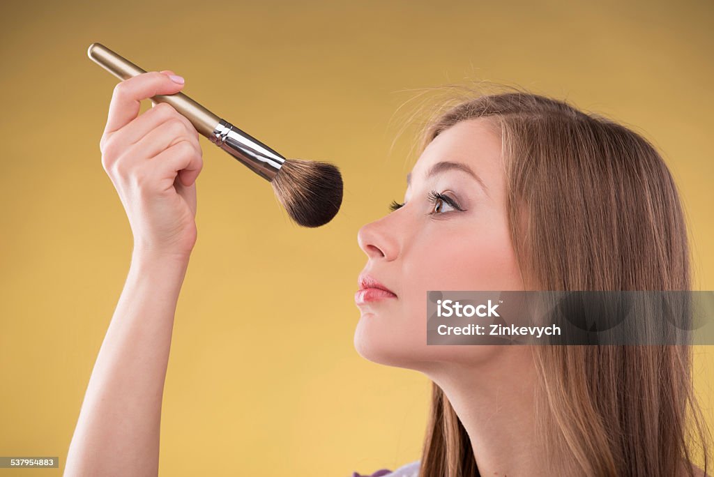 Beautiful brown haired girl Portrait of happy beautiful brown haired girl doing make up with brush for rouge looking aside with copy place close up Adult Stock Photo