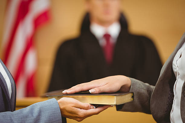 Witness swearing on bible telling the truth Witness swearing on the bible telling the truth in the court room wavebreakmedia stock pictures, royalty-free photos & images