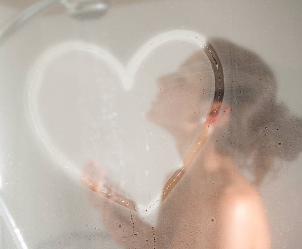 Shower Love, Naked Beautiful Woman Beautiful girl showering with a drawn heart on the steamy shower glass door. Converted from RAW. woman hot shower stock pictures, royalty-free photos & images