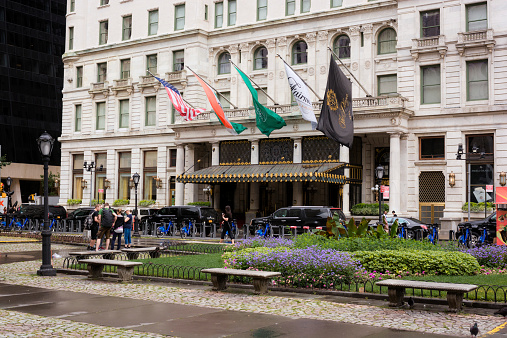 New York City, United States - August 13, 2014: People meander about outside the Plaza Hotel in the Upper Midtown area of Manhattan. The Plaza Hotel, completed in 1907, is a 20-story luxury hotel with a height of 250 feet.