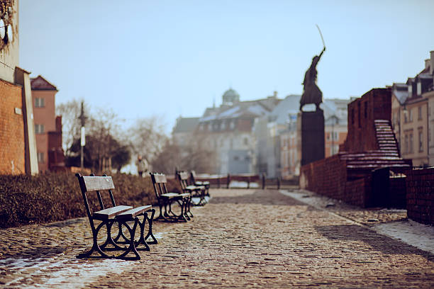 A little alley with old builidngs on both sides and a figure of a monument with sabre