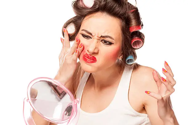 Photo of Nervous woman with curlers removing makeup with her hands