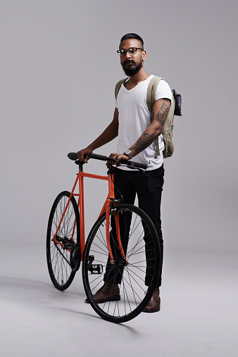 Full length shot of a young man standing with his bicycle in the studio