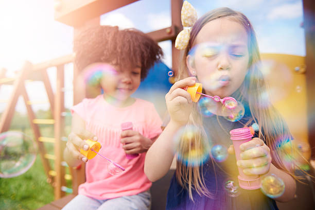 deux filles le joli couper le souffle des bulles de savon - bubble wand child outdoors bubble photos et images de collection