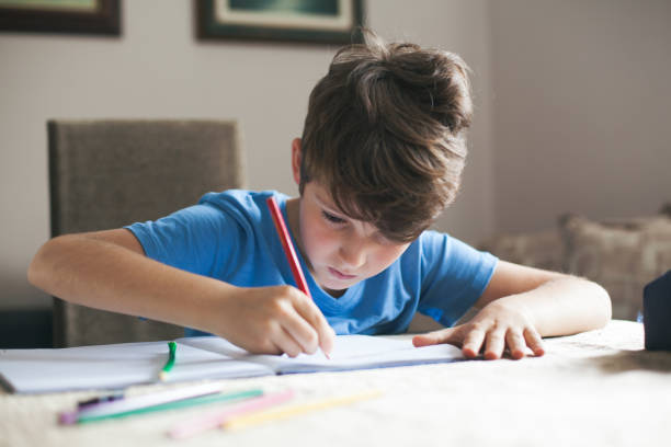 istock Young boy sitting at the table doing his school homework. 538028390