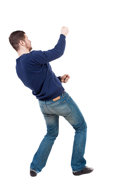 back view of standing man pulling a rope from top back view of standing man pulling a rope from the top or cling to something. guy watching. Rear view people collection.  backside view of person.  Isolated over white background. Man in jeans and a blue sweater pulls the rope on top man touching womans buttock stock pictures, royalty-free photos & images
