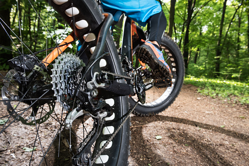 Close up low angle view of fat bike gearshift while the rider is on the trail in the forest.