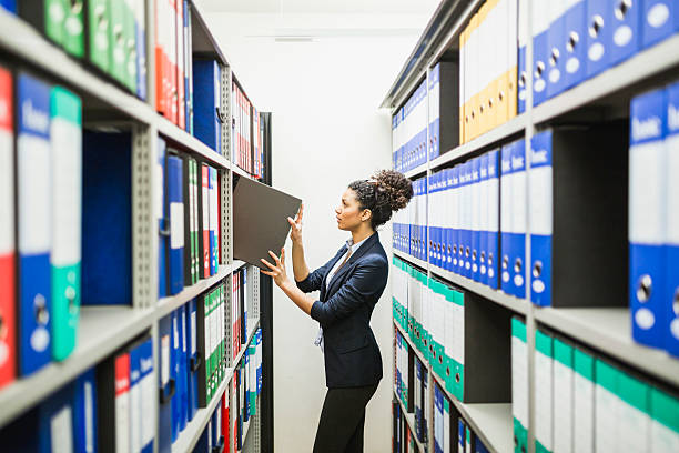 Woman is searching for files in paper archive Secretary working in paper archive filing cabinet photos stock pictures, royalty-free photos & images