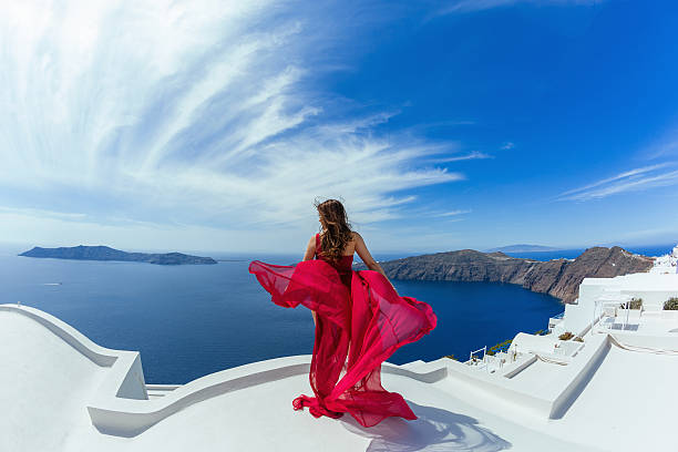 Woman in red dress l on the roof Woman in red dress aerial on the roof of island Santorini woman in red dress stock pictures, royalty-free photos & images