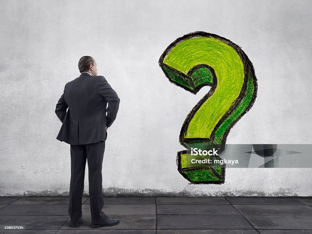 Businessman with Question Mark Painting on the Wall Rear view of businessman standing on sidewalk and looking at the hand drawn question mark painting on the wall. He is looking further, thinking, searching new ideas and way to exit. Adult Stock Photo